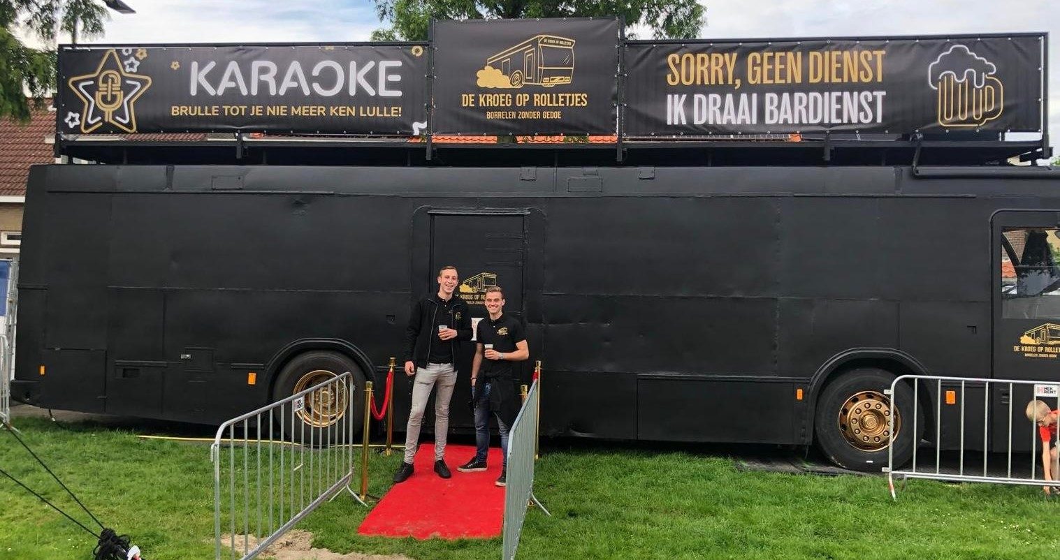 Bart en Perry voor de bus op een grasveld, met rode loper en karaokebanners op het dak.