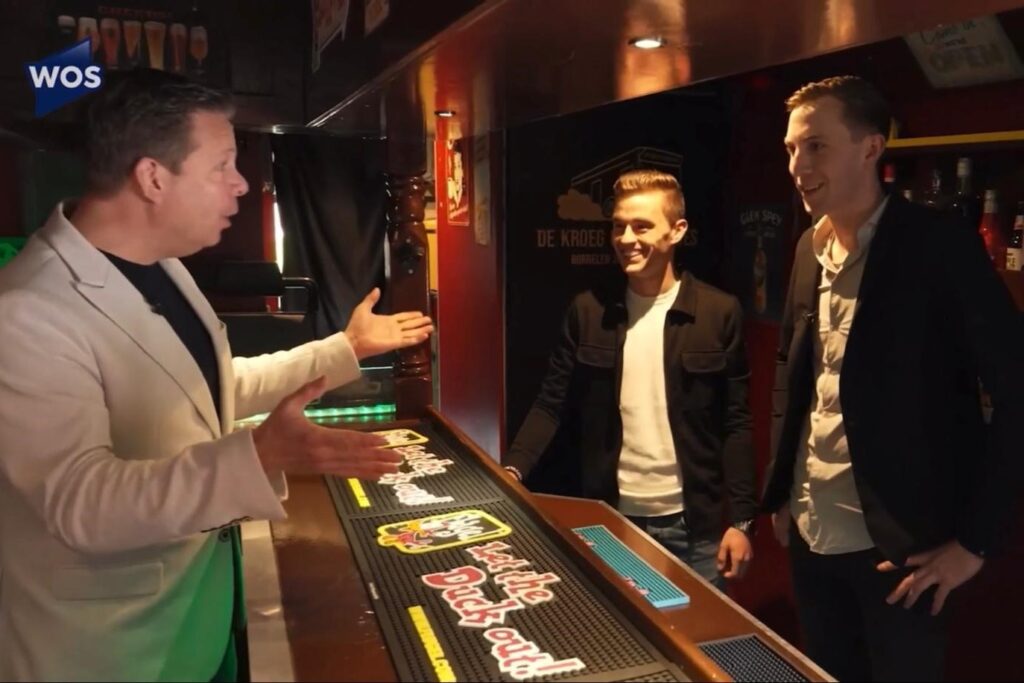 Opname van WOS in de kroeg: presentator in gesprek met Bart en Perry aan de bar.